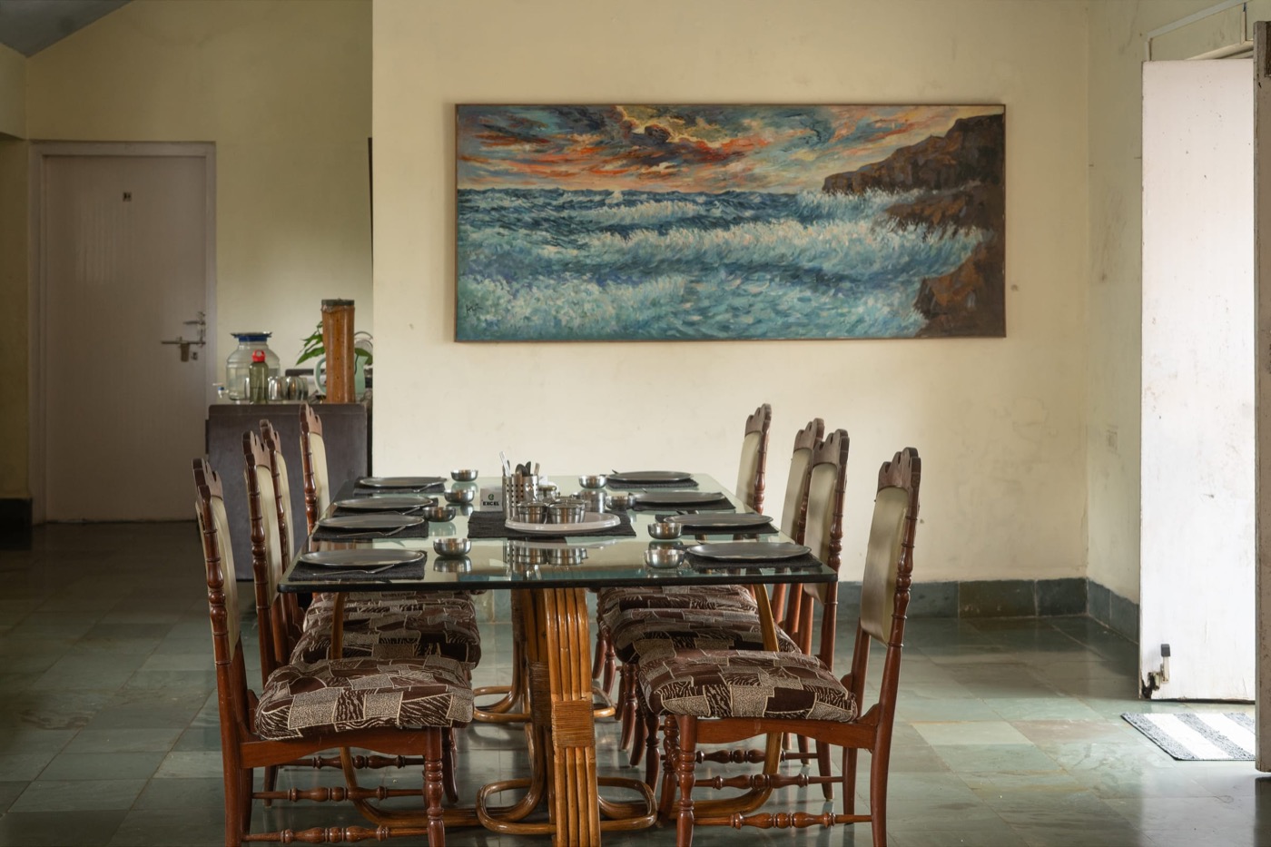The communal dining table set for dinner under a heritage painting