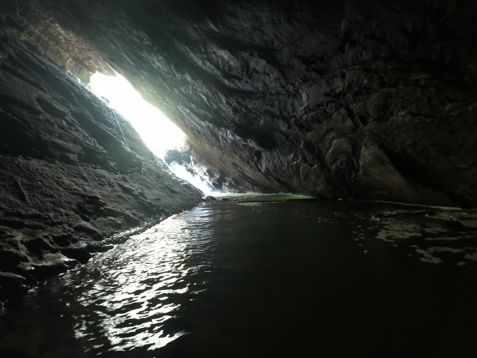 Light streaming through a cave opening onto still water at Ulavi