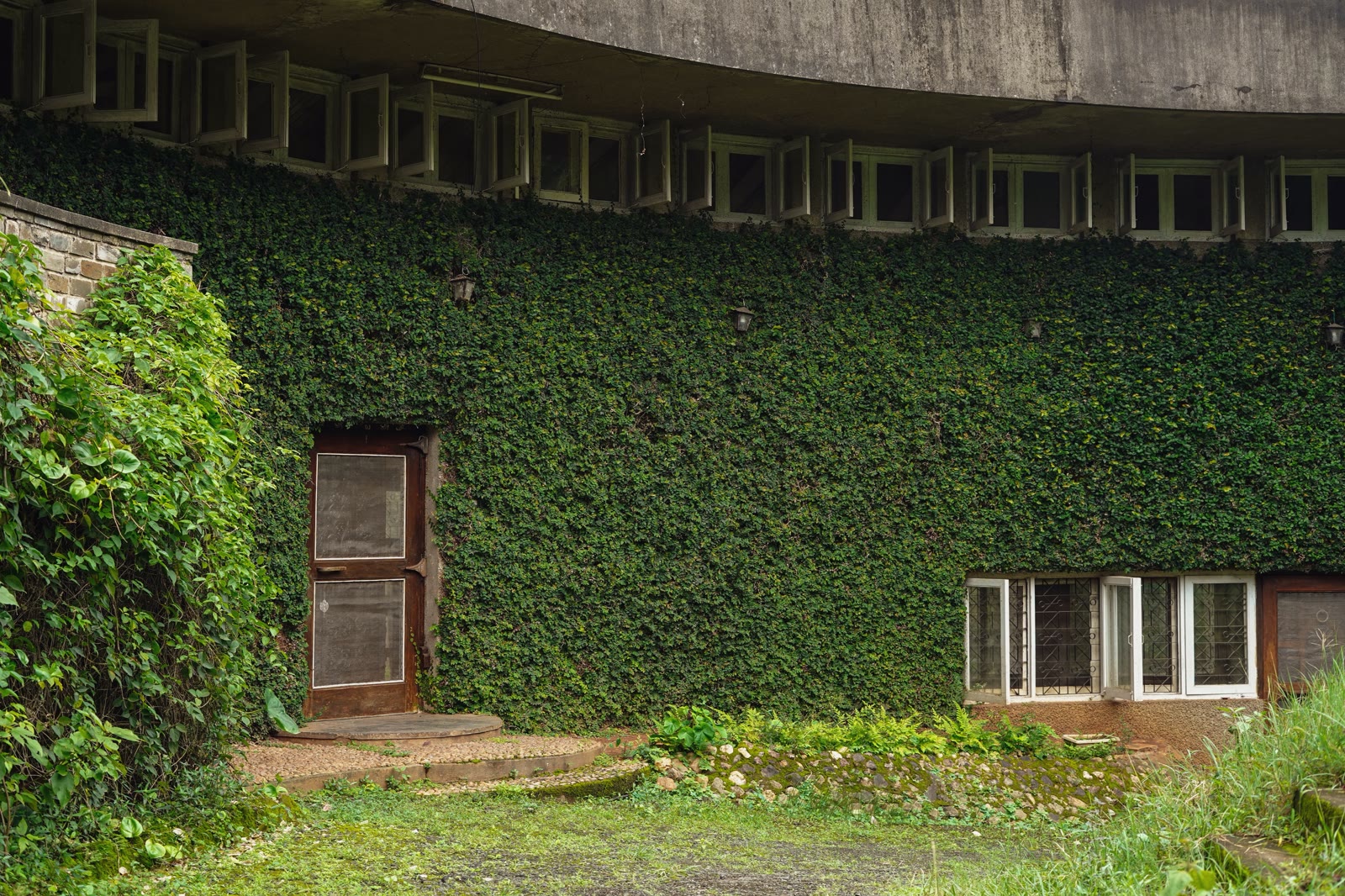 Ivy-covered curved facade of Soch the Space with row of arched windows