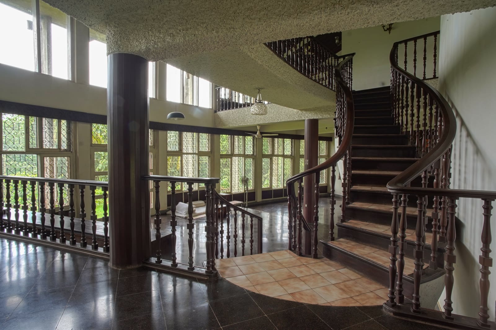 Curved mahogany staircase at Soch with arched windows on every side