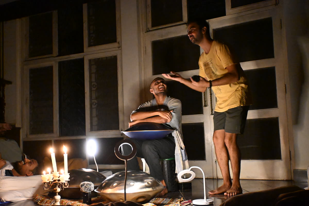 Musician playing handpan in the warm lamplight at Soch