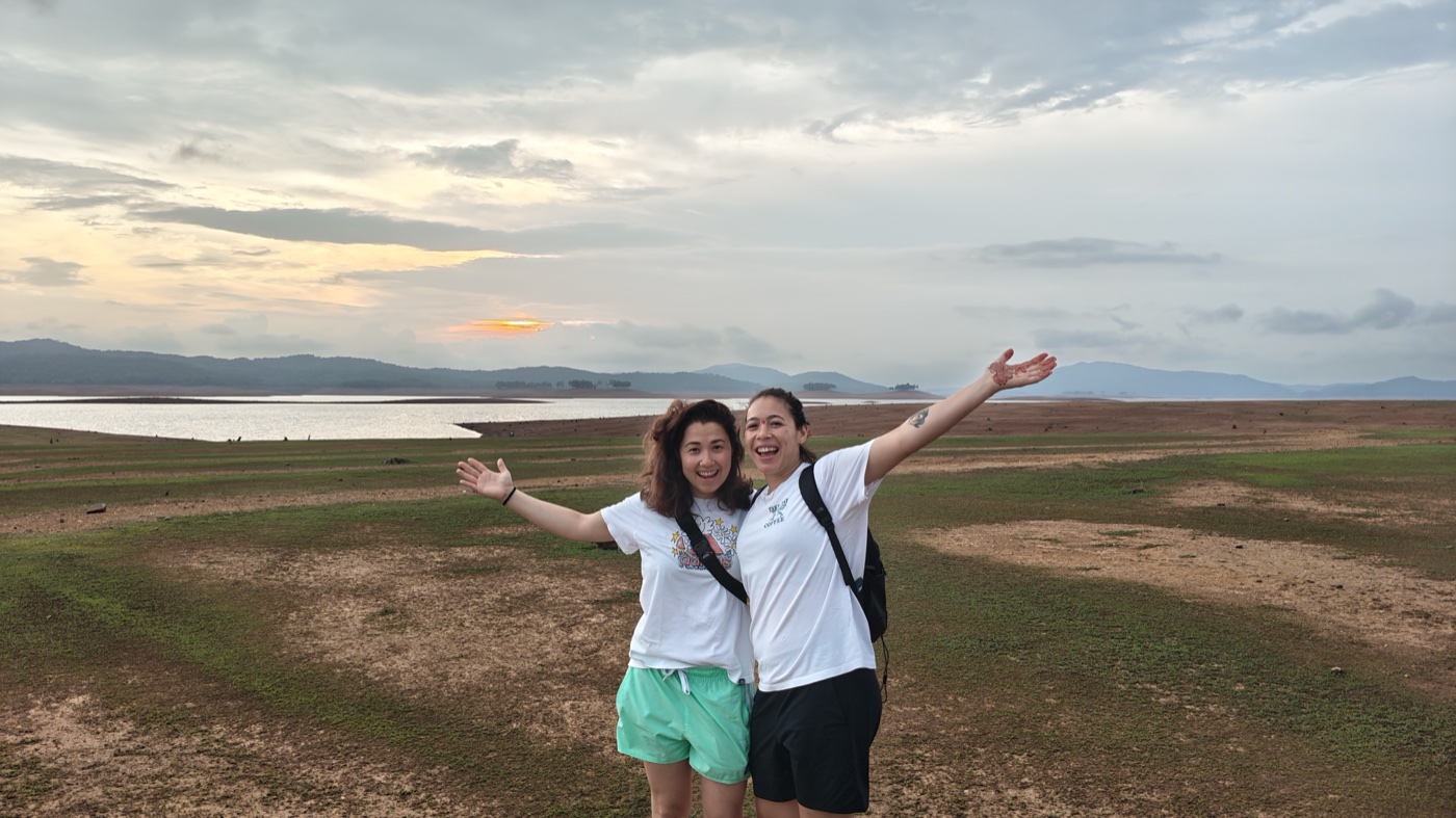 Two women with arms wide open at sunset over the reservoir